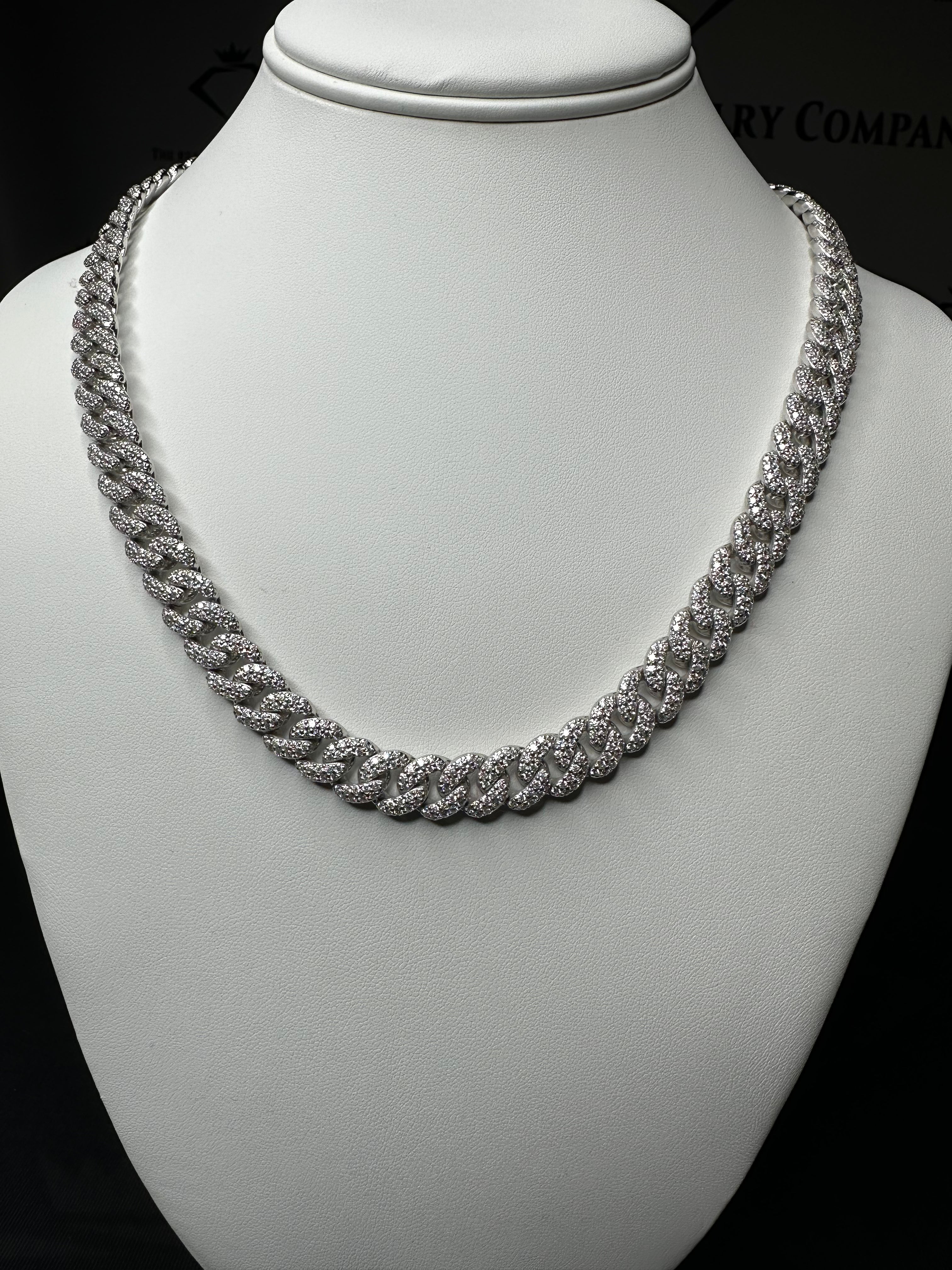 A silver Miami Cuban link chain necklace with encrusted round cut moissanite stones displayed on a mannequin bust.