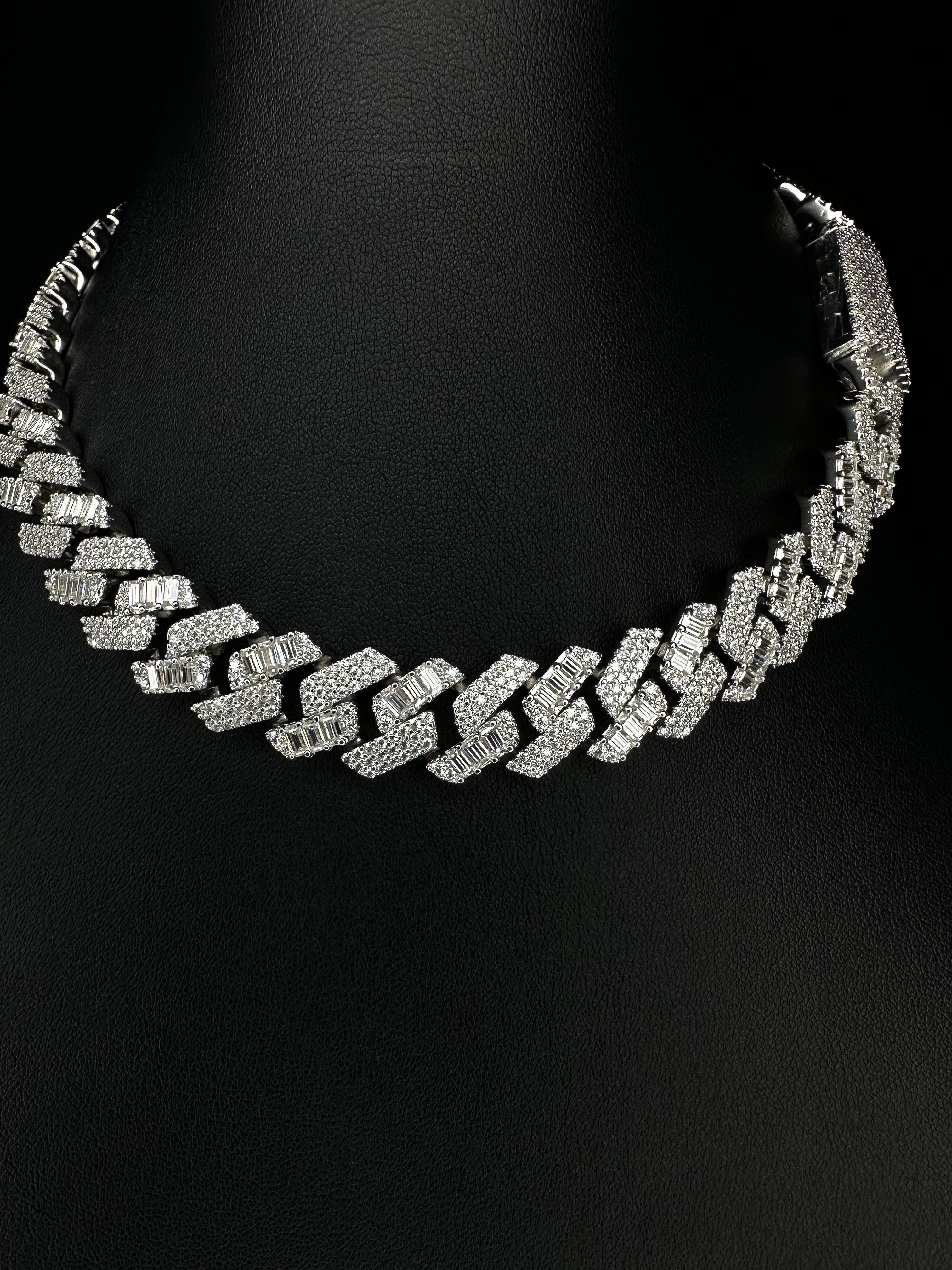 A sterling silver Cuban chain necklace with emerald and round cut moissanite stones set along its length.